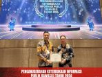 Ketua Bawaslu Minut Rocky Ambar dan Koordinator Sekretariat Michael Polii saat menerima penghargaan Predikat Informatif.